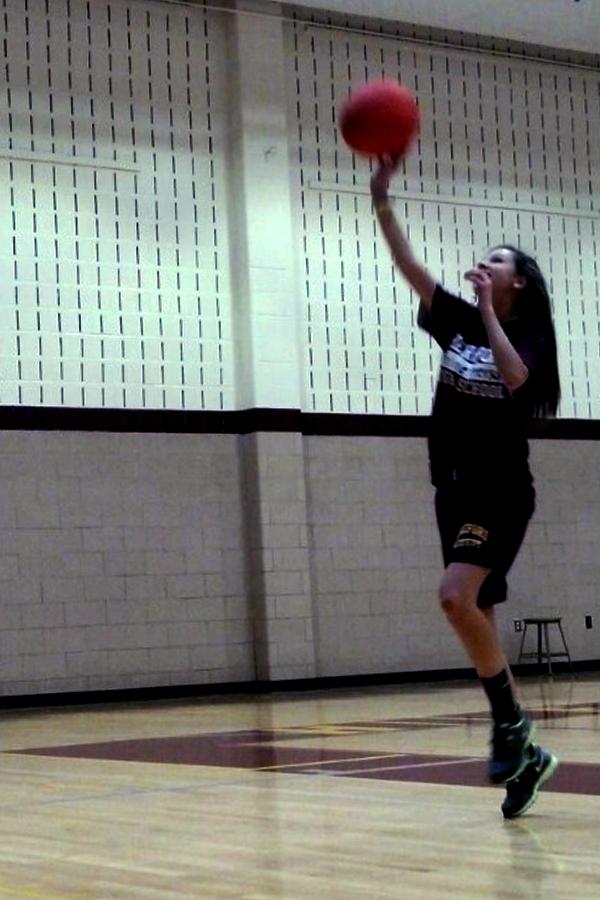 Caroline Peterson (9) shoots a basketball in gym class. Basketball is one of the few activities in which students participate in gym class.