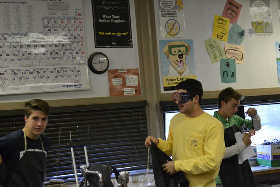 Ryan Rudy (‘15), Stevie Gerovasilis (‘15), and Lucas Spencer (‘15) are put on their goggles and aprons to get ready for the Christmas ornament lab they are about to complete.  Many of the students liked Chemistry club so much because they didn’t need to complete “lab write ups” or use exact measurements.  
