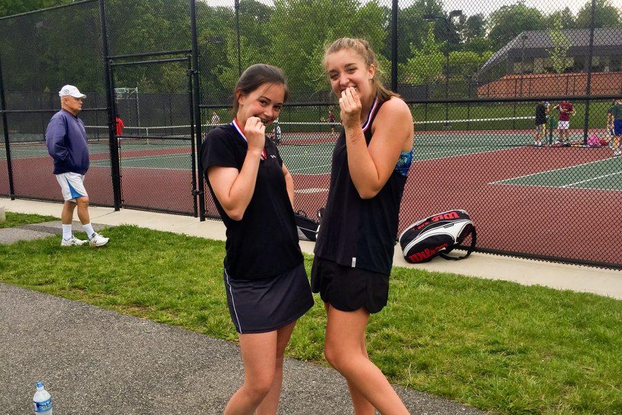 Benson and Reider bite their medals they received for coming in first place for the girls doubles two court in the Baltimore County Tennis Championship.