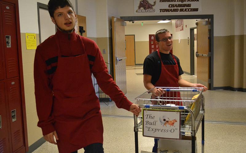 Silas Rock ('17) and Jackson ('17) push the Bulls' Expresso delivery cart through the halls. "[The coffee shop] makes working at Hereford even better," Social Studies teacher Robert Greenwood said. For teachers participating in the secret Santa gift exchange, Clark and the Bull "Express-O" will deliver gifts so teachers can remain anonymous.