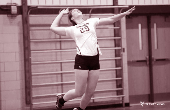 As one of the team's top servers this year, Erin Collins jumps into the air to give a solid serve over the net.