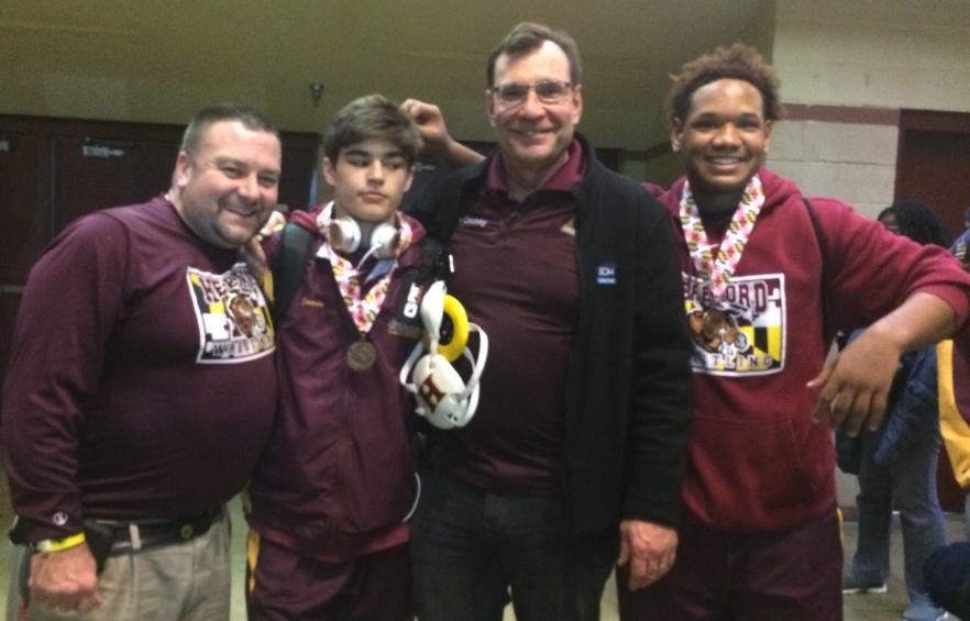 Wrestling Coach Brett Baier, Jimmy Cavin (17), Coach Ron Causey, and Troy Gladney (17) stand together for one last picture. Gladney and Cavin wrestled their last matches with the high school team at states on March 5.