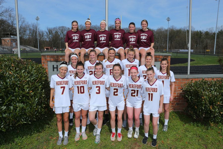  The girls Varsity Lacrosse team gets their picture taken before their game. It is a traditionthat the seniors sit on top of the wall in the back. 