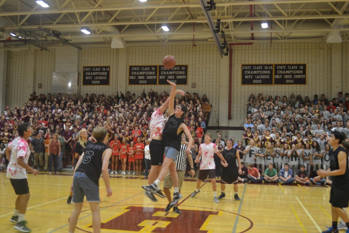 As the two players from the Senior and Upperclassman team jump for the ball teammates stood waiting for a chance to score the first points.