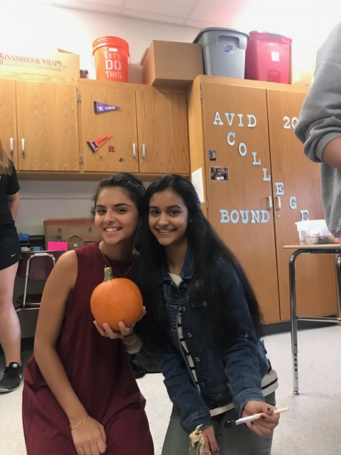 Students pose for a picture holding pumpkins. The pumpkins were donated to an assisted care center after they were painted.