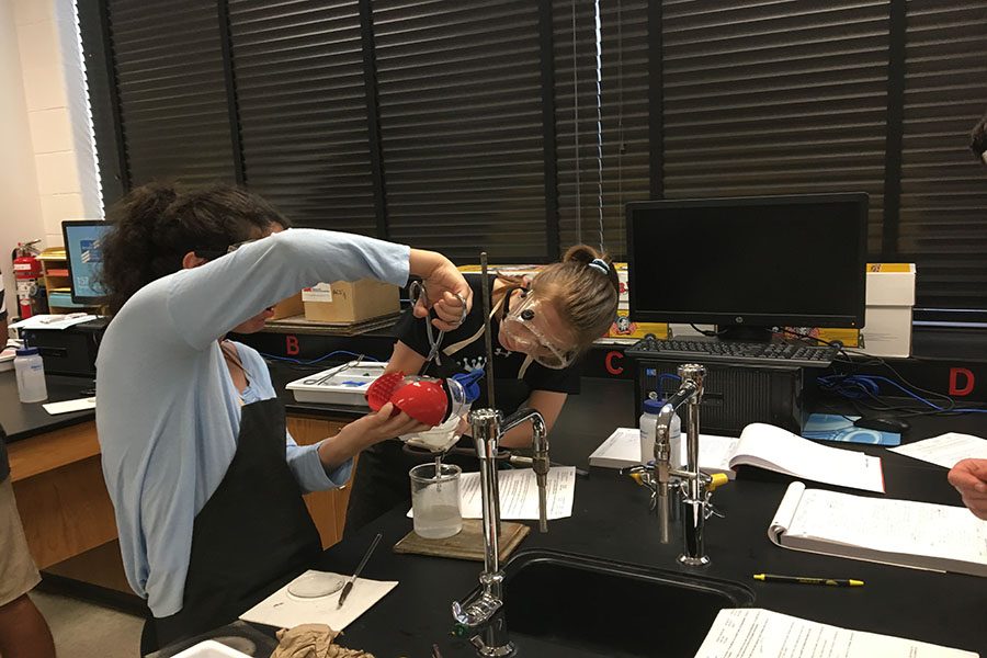 
Sydney Jenkin (’20) assists Beata Assadi (’19) as she pours a substance into their filter paper.
“We’re working with reaction stoichiometry which is important for a lot of labs we’ll be doing [later in the year],” said Jenkin. “I think it’s really interesting seeing what reactions look like and doing labs you wouldn’t ordinarily do in GT or Honors Chemistry.”
