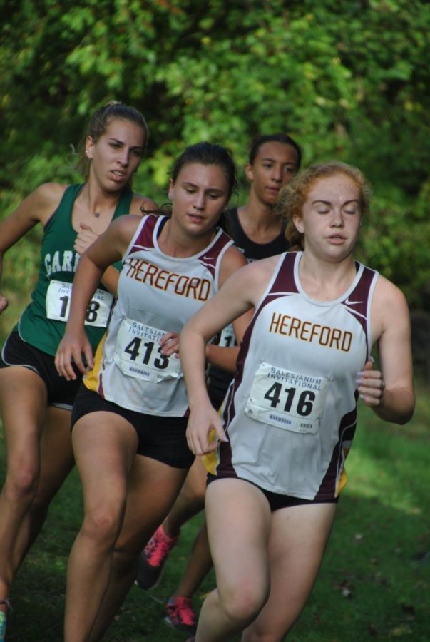 Emily Francis('19) and Nicole Burkowski ('18) push each other to finish the race. The cross country team won counties this year.