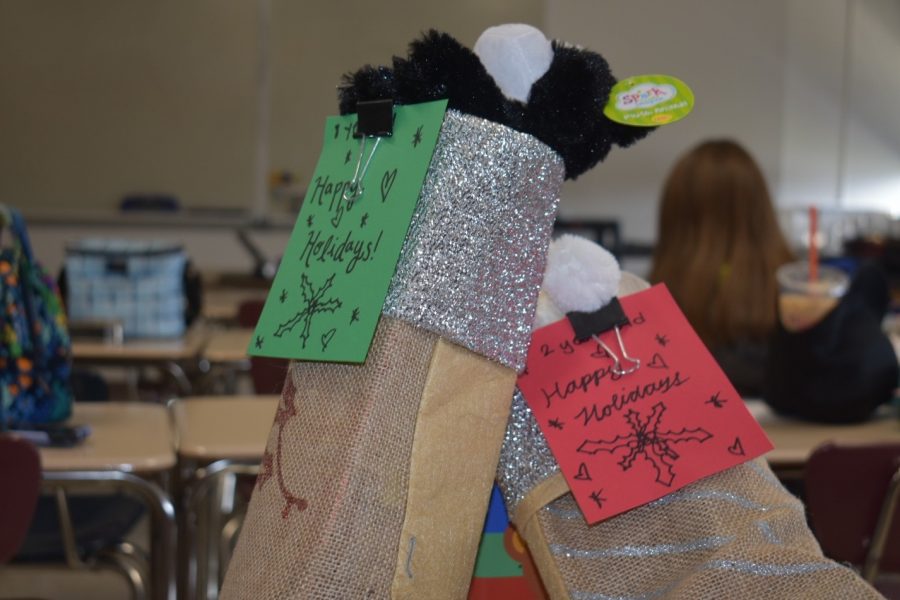 Decorating cards for their stockings, members of the Acts of Kindness Club held up the collected items for House of Ruth. 