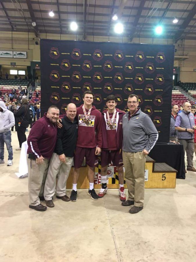 Mr. Baier and other wrestling coaches, pose with Jimmy Kells (19) and Cale McMurdy (18), who placed at the meet.
