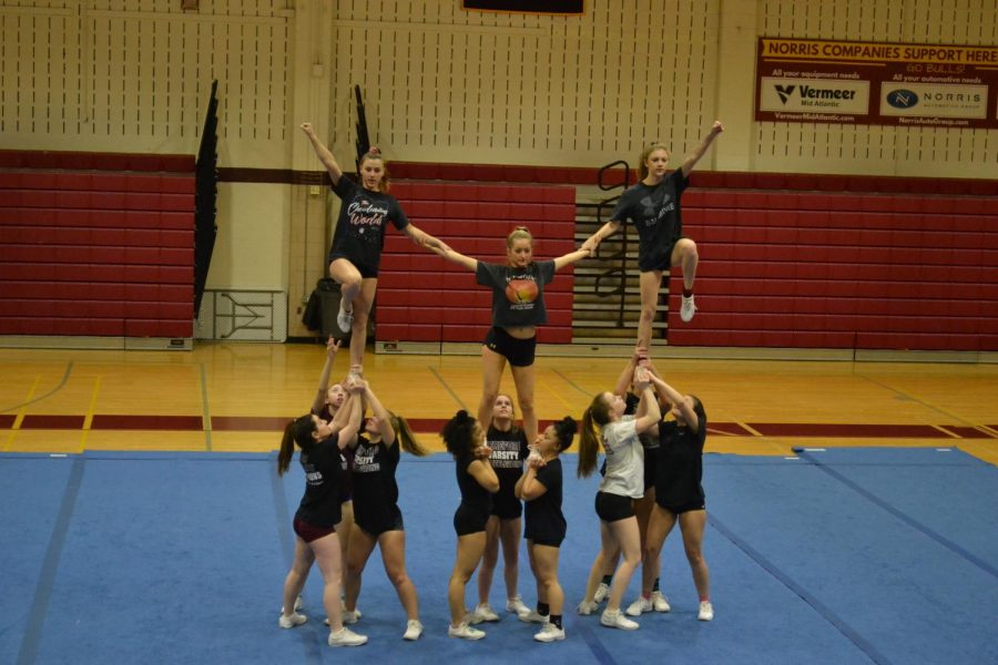 Emma DiVenti ('22) supports her teammates during their stunt. The team practiced this move daily to perfect it.