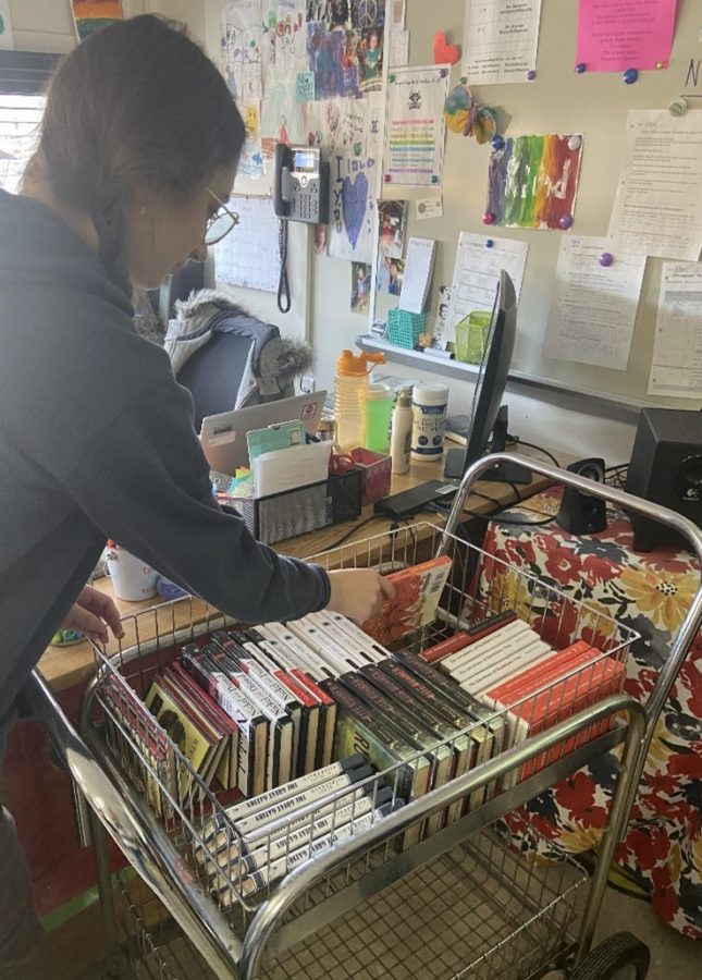 Claire White (‘23) pulls “The Catcher in the Rye” by J. D. Salinger from the array of banned books in Mrs. Houseknecht’s room. Salinger’s novel was removed from curriculum in Summerville, SC in 2001 due to parent complaints about the filthy, filthy book. 