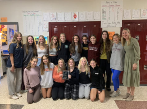 The JV field hockey team shows off their county championship plaque outside of Coach Coburns room, since they couldnt celebrate on the field.