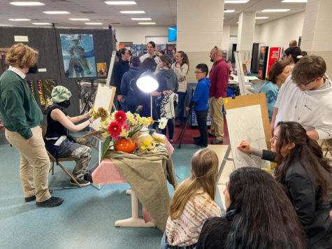Students and families explore the art show. Live still life portraiture was one of the many interactive exhibits.