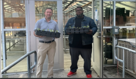 Anthony Mikalauskas (left) and Alex Smith (right) pose in front of Hereford’s greenhouse, holding a small portion of the plants donated by Hereford’s Garden Club. 