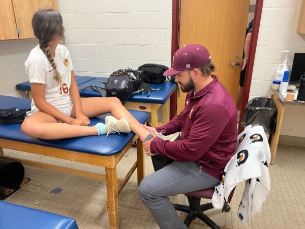 Cook helping Sophia Rongione(´26) tape her ankle before soccer practice.